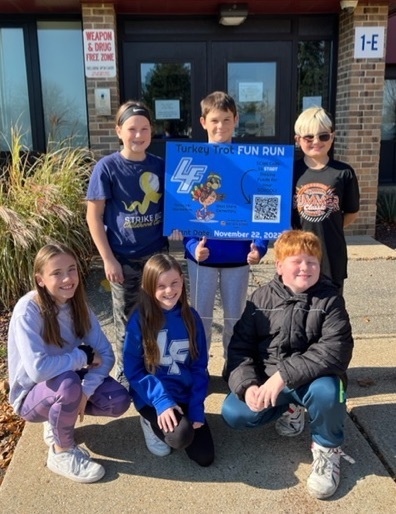 group of students holding a Turkey Trot sign donated by UPS Store