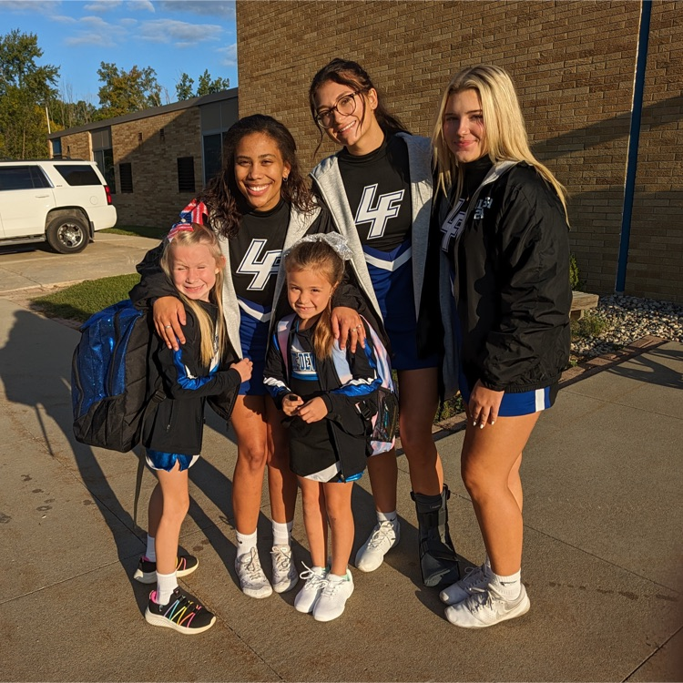 cheerleaders posing in front of school