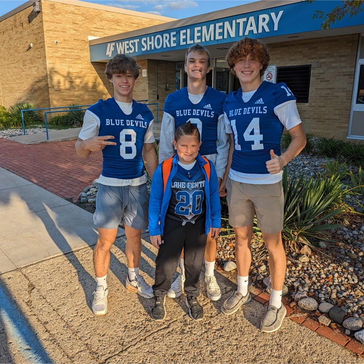football players posing in front of school