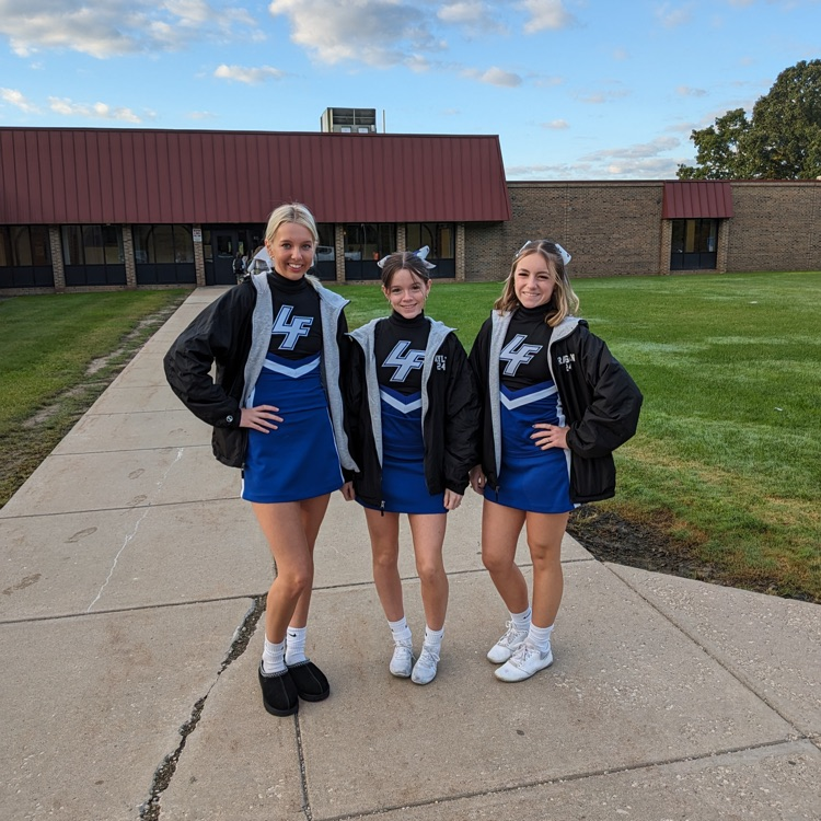 cheerleaders posing in front of school
