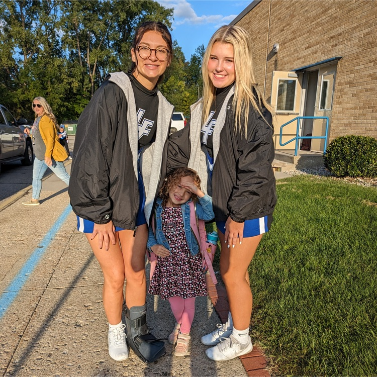 cheerleaders posing with student in front of school