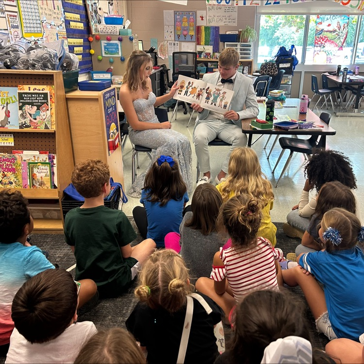 2 seniors reading to a class of second graders