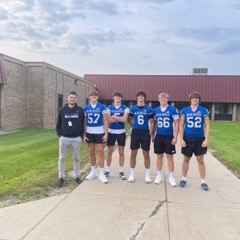 football players posing in front of school
