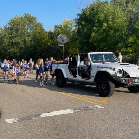 girls basketball team following g white Jeep in parade