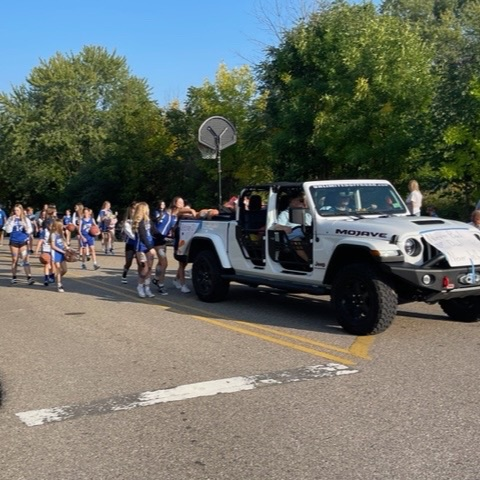 girls basketball team following g white Jeep in parade 