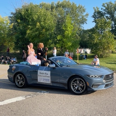 homecoming court riding on grey convertible